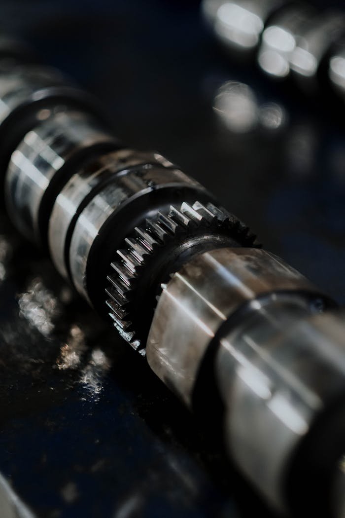Detailed image of a camshaft showcasing gears and reflections on a dark surface.